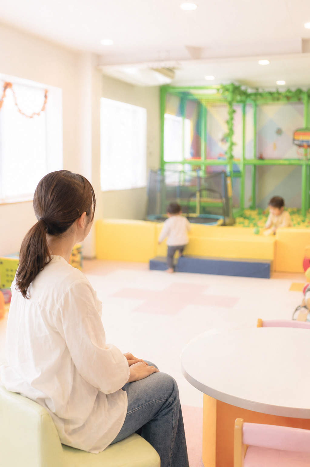 小さな子供が遊んでいるのを遠目に見守るお母さんの画像